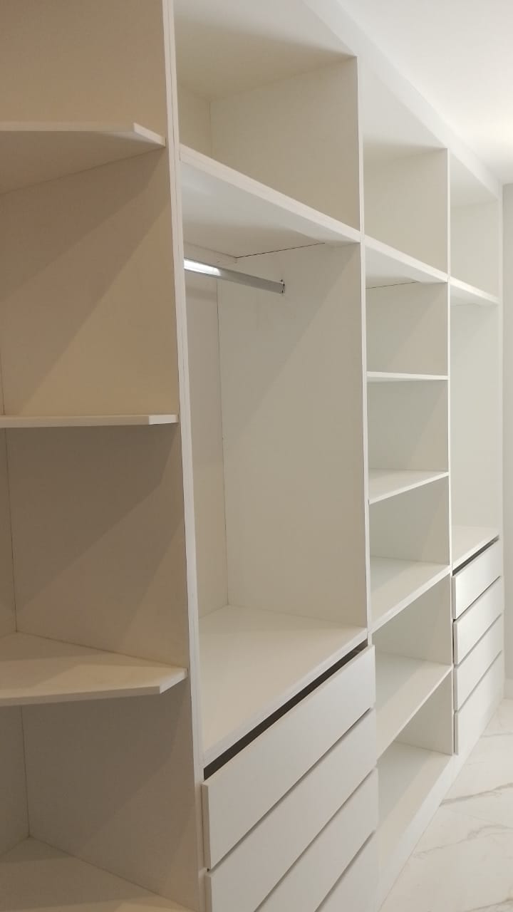 Closet planejado com nichos, gavetas e cabideiro iluminado